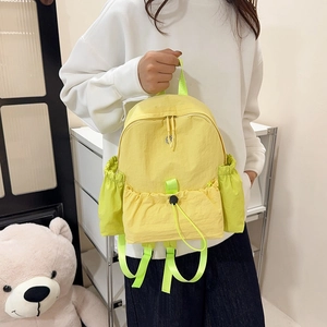 Details des gelben Nylon-Rucksacks mit neongrünen Kordelzug-Seitentaschen und Doppelgriffen