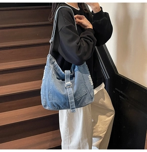 Detail of vintage washed denim tote bag featuring distressed edges and stylish buckles