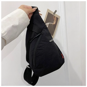 Close-up of black nylon chest bag with metal zipper and adjustable woven strap detail