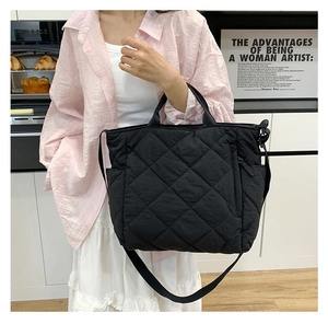 Detail view of quilted black tote bag showing side pocket and durable nylon texture