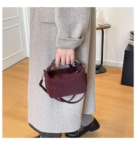 Détail du sac à main bordeaux en cuir avec finitions dorées et bandoulière réglable