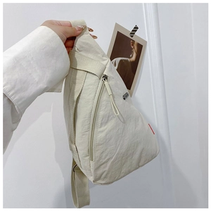Detail of cream nylon crossbody chest bag showing fabric texture and adjustable strap