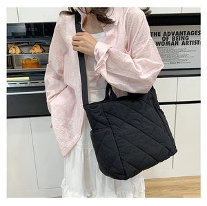 Quilted black tote bag detail showing diamond stitching and adjustable nylon strap