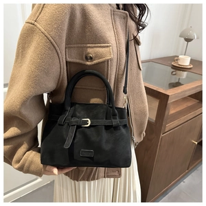 Detailed close-up of a black faux suede tote bag featuring a decorative buckle and metal logo