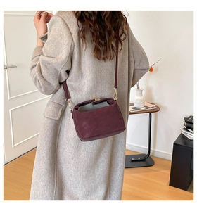 Détail du sac bandoulière en daim bordeaux avec boucle dorée et bandoulière en cuir