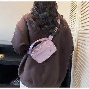 Detail of lavender nylon crossbody bag showing the round logo and wide shoulder strap