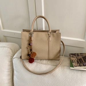 Elegante beige gewebte Tragetasche mit Ledergriffen und dekorativem Quastenanhänger