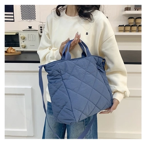 Close-up of blue quilted nylon tote bag with rhombus pattern and adjustable strap