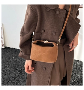 Sac bandoulière en daim marron avec fermoir vintage en métal porté par un mannequin
