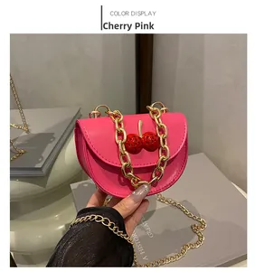 Détail du mini sac bandoulière rose fuchsia avec chaîne dorée et décor cerise brillant