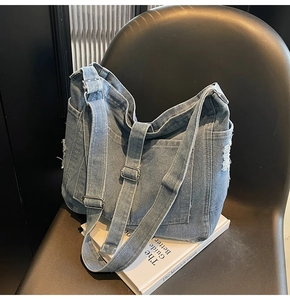Detailed side view of washed denim tote with frayed edges on a minimalist chair
