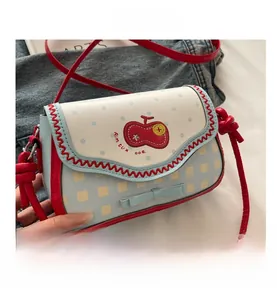 Detail view of mini crossbody bag featuring red cherry embroidery and blue plaid pattern