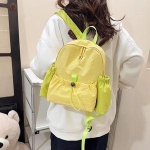 Gelbgrüner Nylon-Rucksack mit Kordelzug-Fronttasche auf dem Rücken eines Frauenmodells