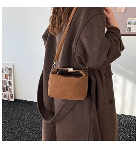 Vue détaillée du sac bandoulière en daim caramel porté sur un manteau en laine sombre élégant