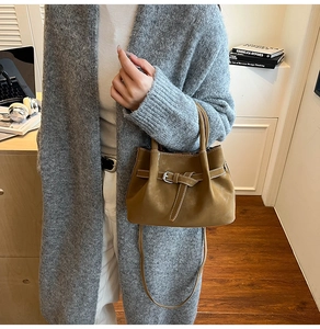 Close-up of tan matte leather handbag with belt buckle detail and thin shoulder strap