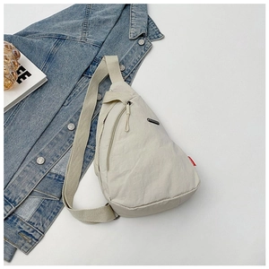 Detailed macro shot of the off-white nylon chest bag on a casual blue denim jacket
