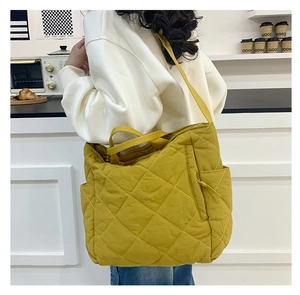 Macro detail of the bright yellow quilted tote bag showing rhombus stitching and side pocket