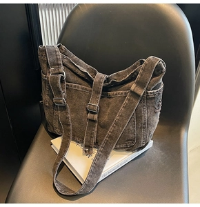 Detail of washed black denim tote bag featuring retro frayed edges and silver metal buckles