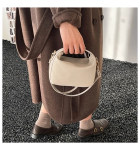Détail d'un sac bandoulière beige minimaliste avec poignée dans un décor de mode d'automne