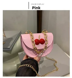 Mini sac à bandoulière rose avec chaîne dorée et ornement cerise rouge brillant