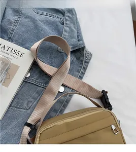 Detail of khaki nylon crossbody bag with adjustable wide strap and secure buckle