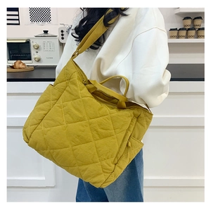Detail of a bright yellow quilted puffer tote bag with diamond stitching and side pocket