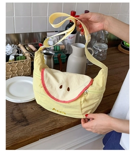 Close-up of yellow apple-themed canvas crossbody bag with embroidered detail and strap