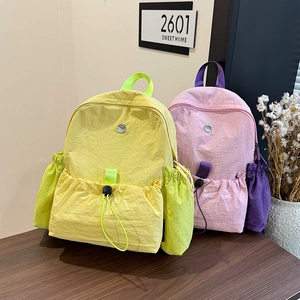 Modische Nylon-Rucksäcke in Gelb und Rosa auf einem Tisch für Schule oder Reisen