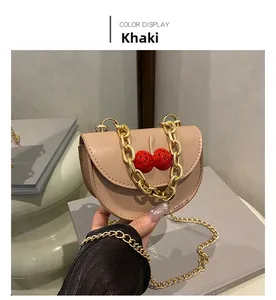 Détail du mini sac à bandoulière kaki avec cerises décoratives et chaîne dorée