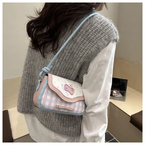 Detail of plaid crossbody bag with pink bow and cartoon badge on a female model