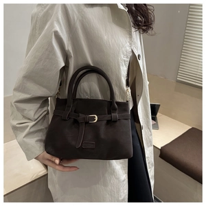 Macro detail of dark brown faux suede tote bag featuring metallic buckle and Fashion label