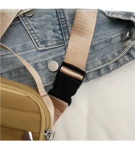 Detail of durable black plastic buckle and adjustable nylon strap on khaki crossbody bag