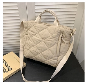 Detail view of the quilted tote bag showing the side zipper pocket and soft fabric texture