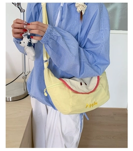 Detail of light yellow canvas crossbody bag featuring a creative apple slice embroidery