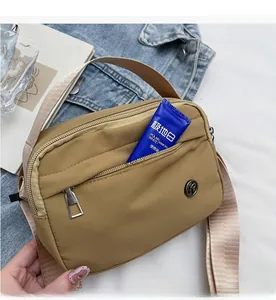 Detail view of the khaki nylon crossbody bag featuring multiple functional zipper pockets
