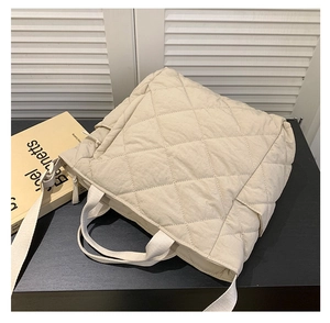Detailed side view of beige quilted tote bag showing zipper and soft nylon fabric