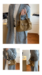 Detail showing caramel brown crossbody bag with belt strap buckle and plush dog charm
