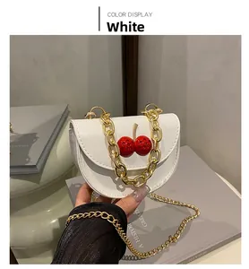 Détail du mini sac blanc à bandoulière avec décor cerise et chaînes dorées