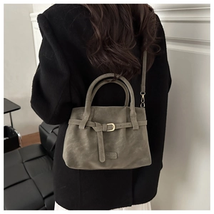 Detailed view of grey-green faux suede tote bag with metal buckle and fashion logo