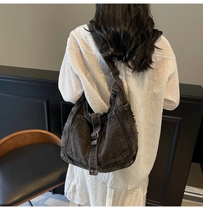 Detail of a large hobo denim crossbody bag with adjustable metal buckles and retro finish