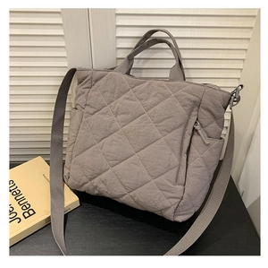Detail of grey quilted tote bag featuring diamond stitching and side pocket design