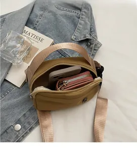 Internal view of the khaki nylon crossbody bag showing storage space for phone and wallet