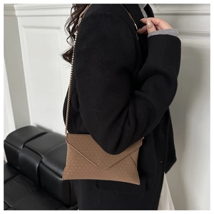 Detail of tan envelope crossbody bag with geometric embossing and gold chain strap