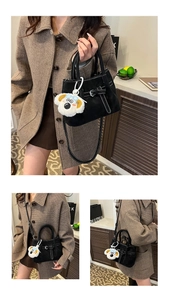 Detail showing black textured handbag with contrast stitching and decorative belt buckle