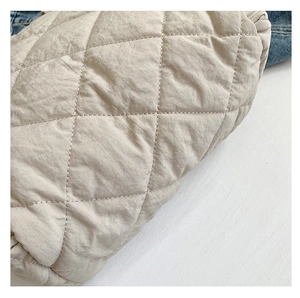 Close-up of beige quilted canvas fabric with diamond stitching and soft texture