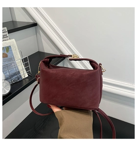 Détail macro d'un sac à main bordeaux en cuir avec fermoir doré et poignée fixe