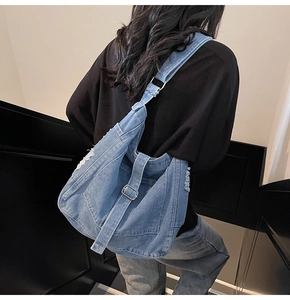 Detailed view of washed vintage denim tote bag featuring distressed fringe and metal buckle
