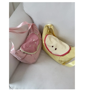 Nylon fruit-shaped crossbody bags in watermelon and lemon designs on a soft sofa