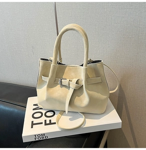 Detailed macro view of the creamy white textured suede surface and strap detail of the bag