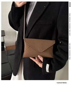 Close-up of brown envelope crossbody bag with woven texture and gold chain strap